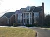 A large brick house with a lawn

Description automatically generated